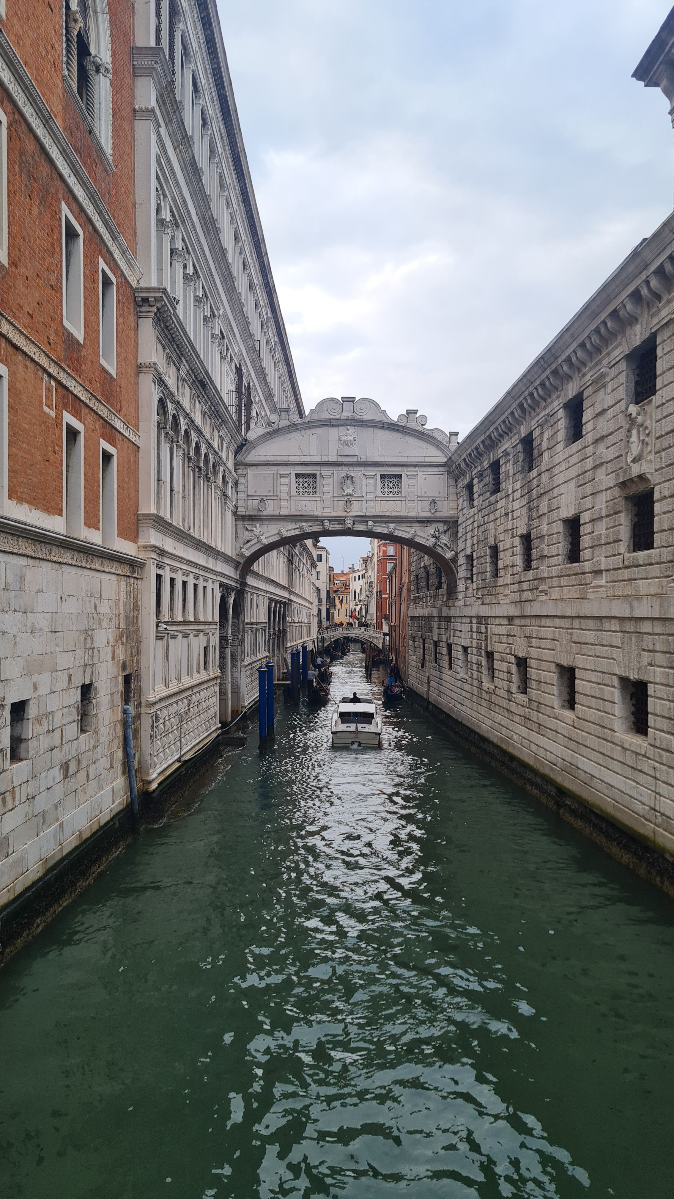 The Bridge of Sighs spanning a narrow green canal between two stone buildings, Venice