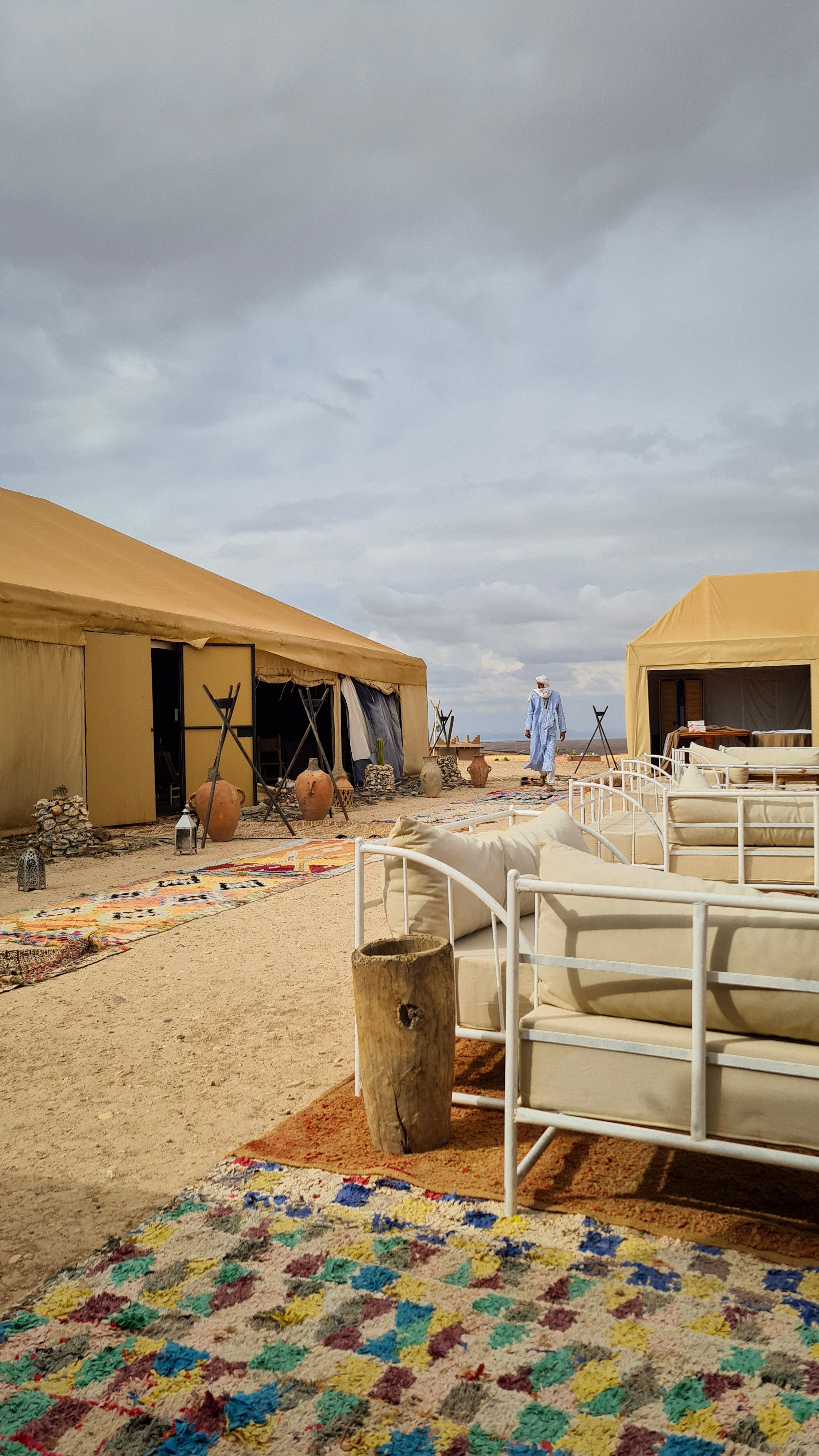 Sand-colored tents, white sofas and a colorful rug at a desert camp, Agafay Desert