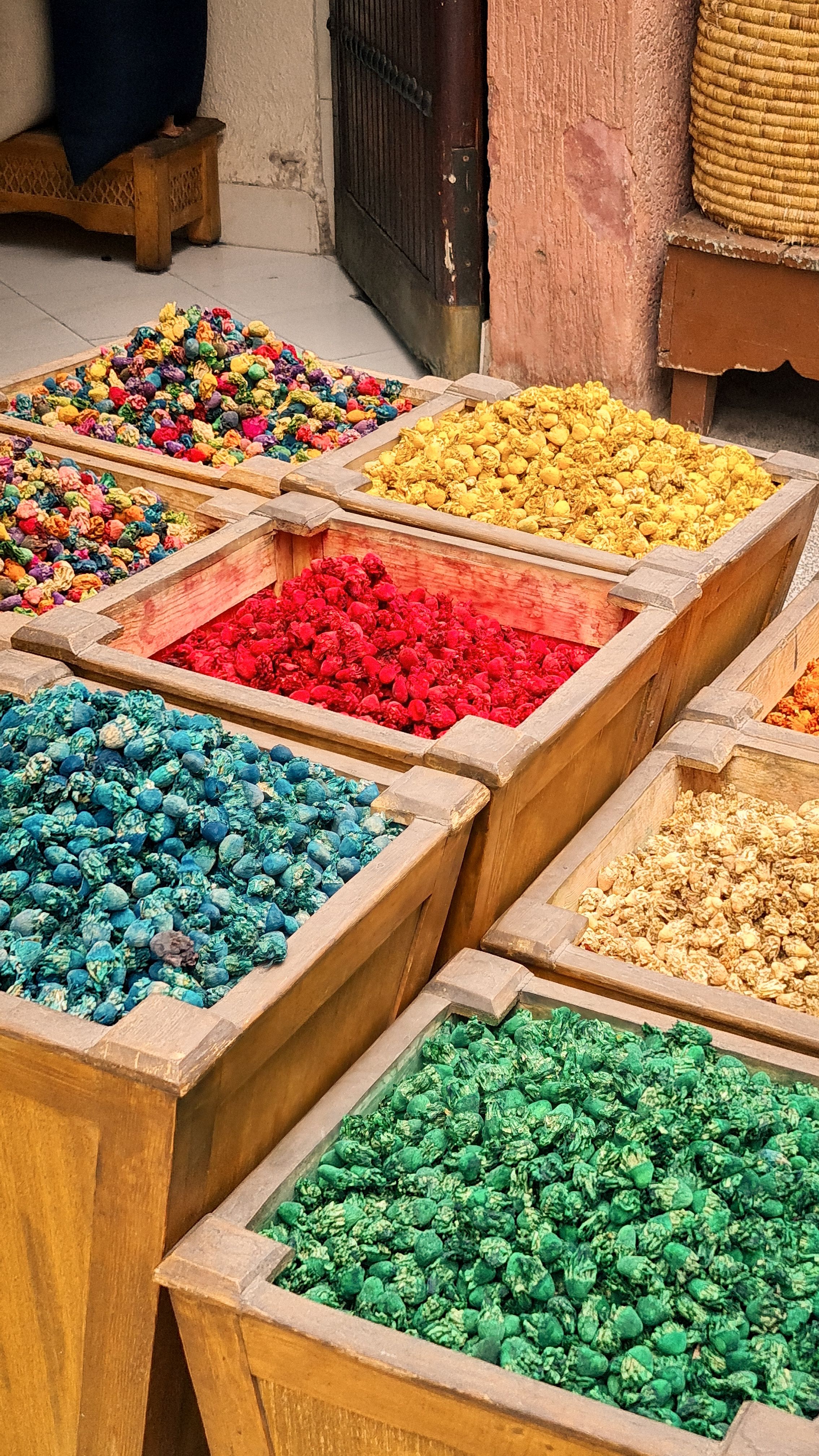 Wooden bins filled with dried flowers and bright blue, red and green pigments in a souk, Marrakech