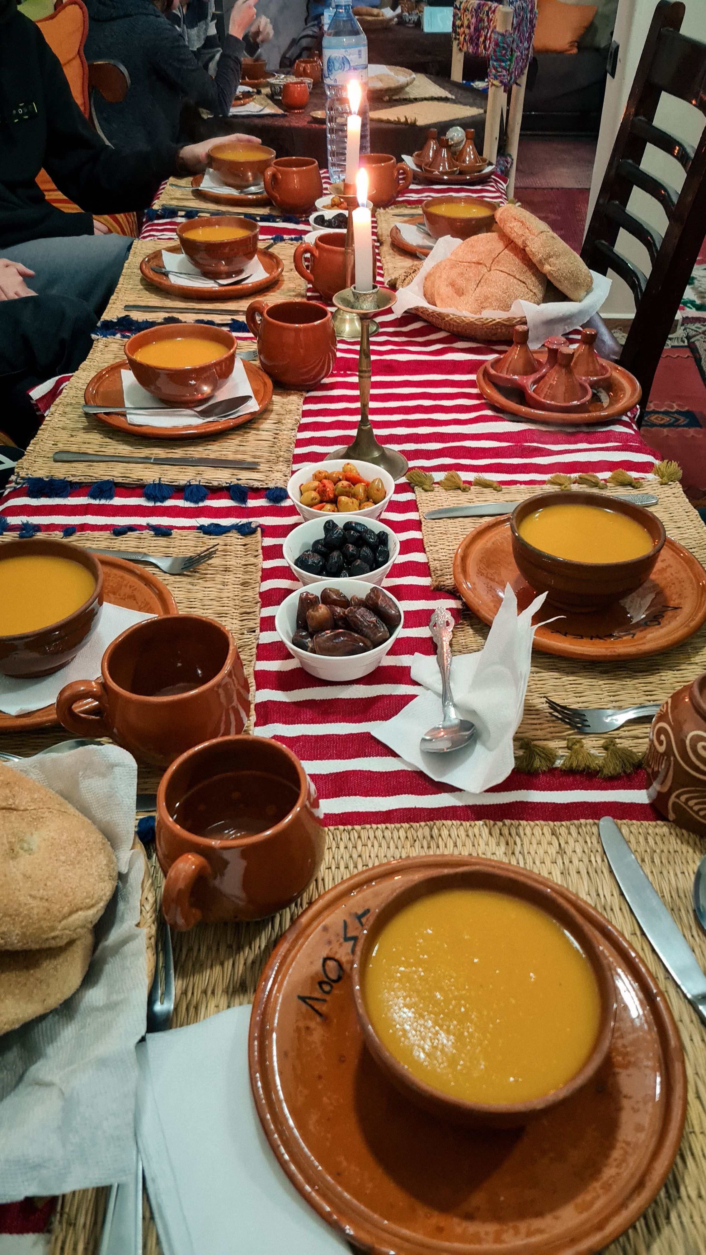 A long table set with clay bowls of soup, bread, dates and olives, Imlil
