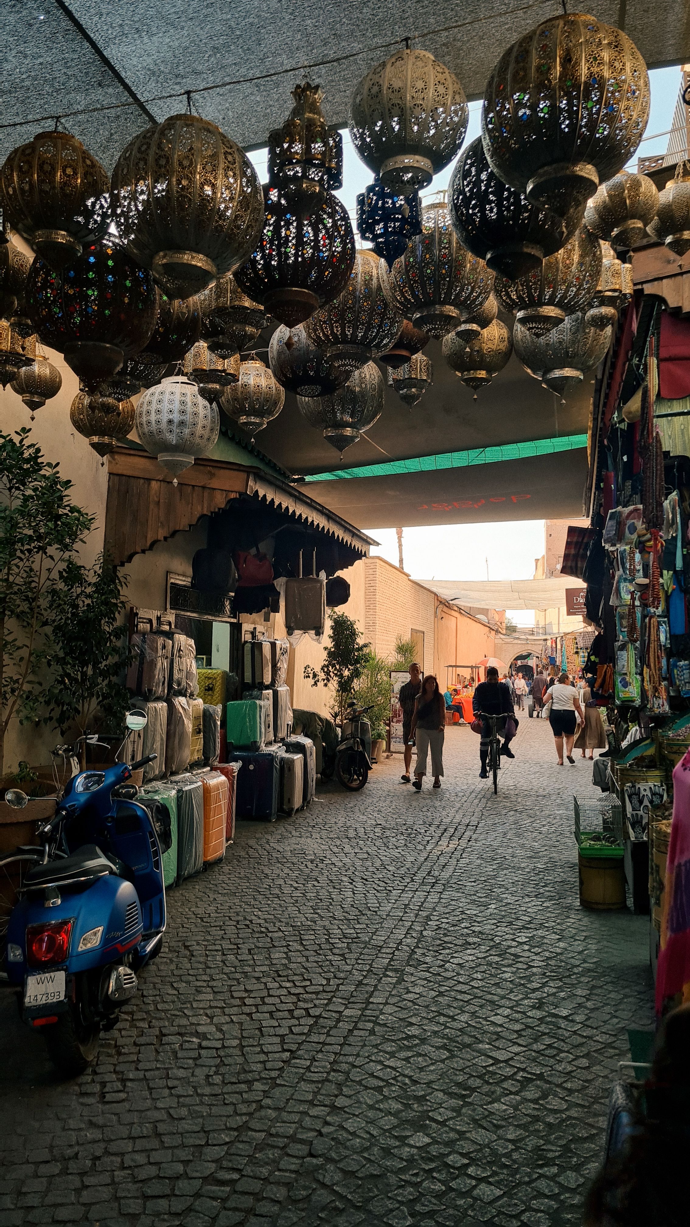 Pierced metal lanterns hanging above a cobbled souk lane in the evening light, Marrakech