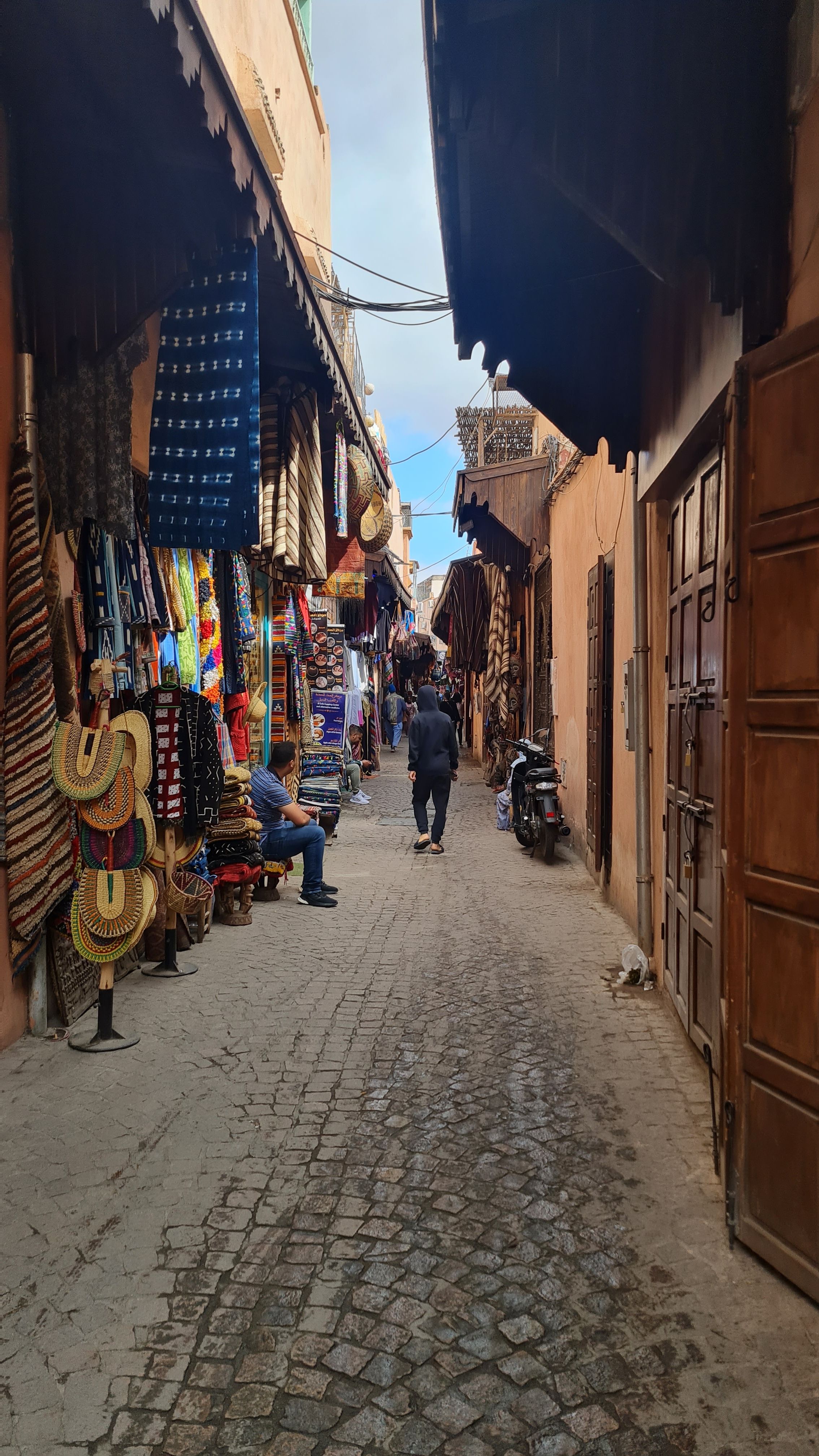A narrow market street lined with textiles and handicrafts, Marrakesh