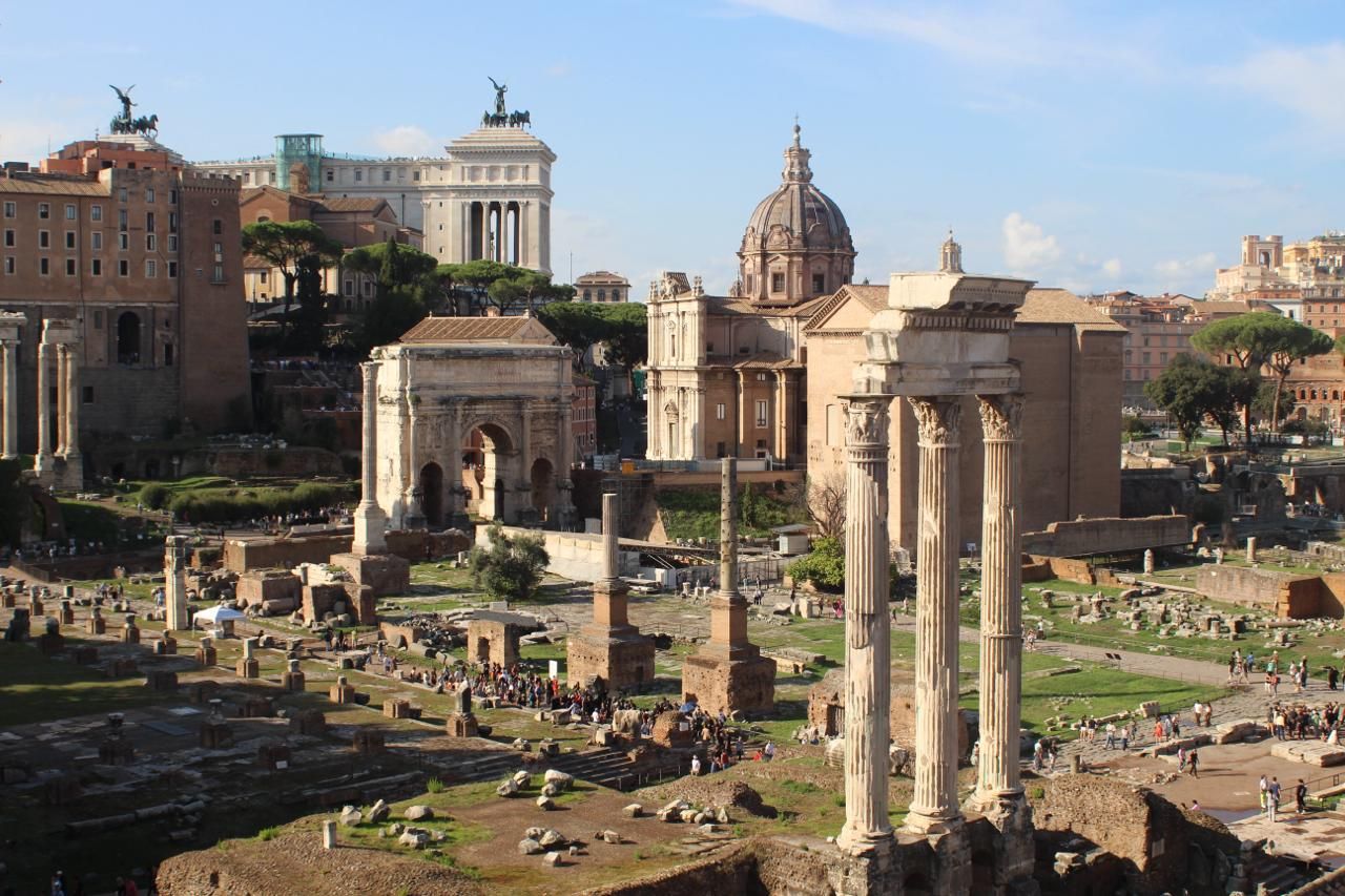 Standing columns and an ancient arch among the ruins of the Roman Forum in warm afternoon light, Rome