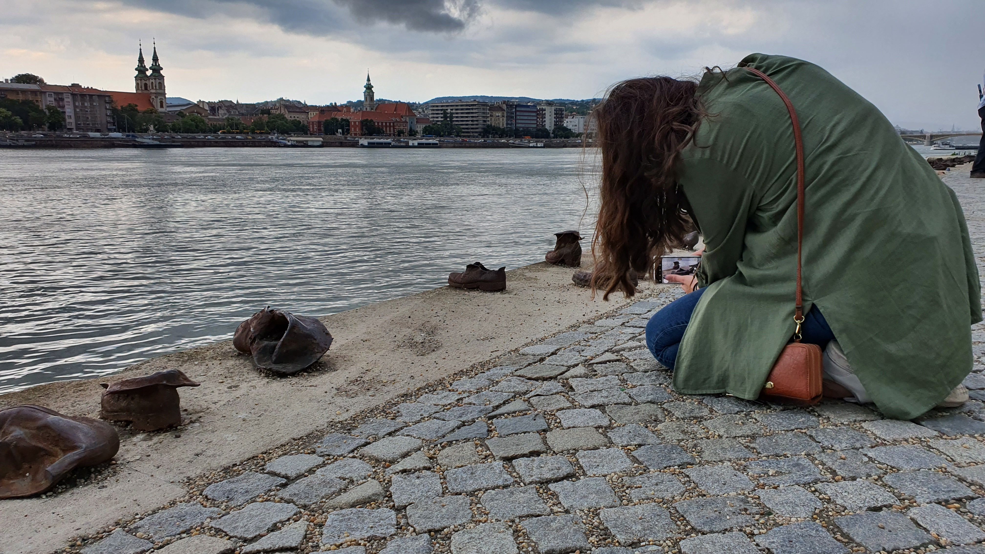 A woman photographing the Shoes on the Danube Bank memorial, Budapest