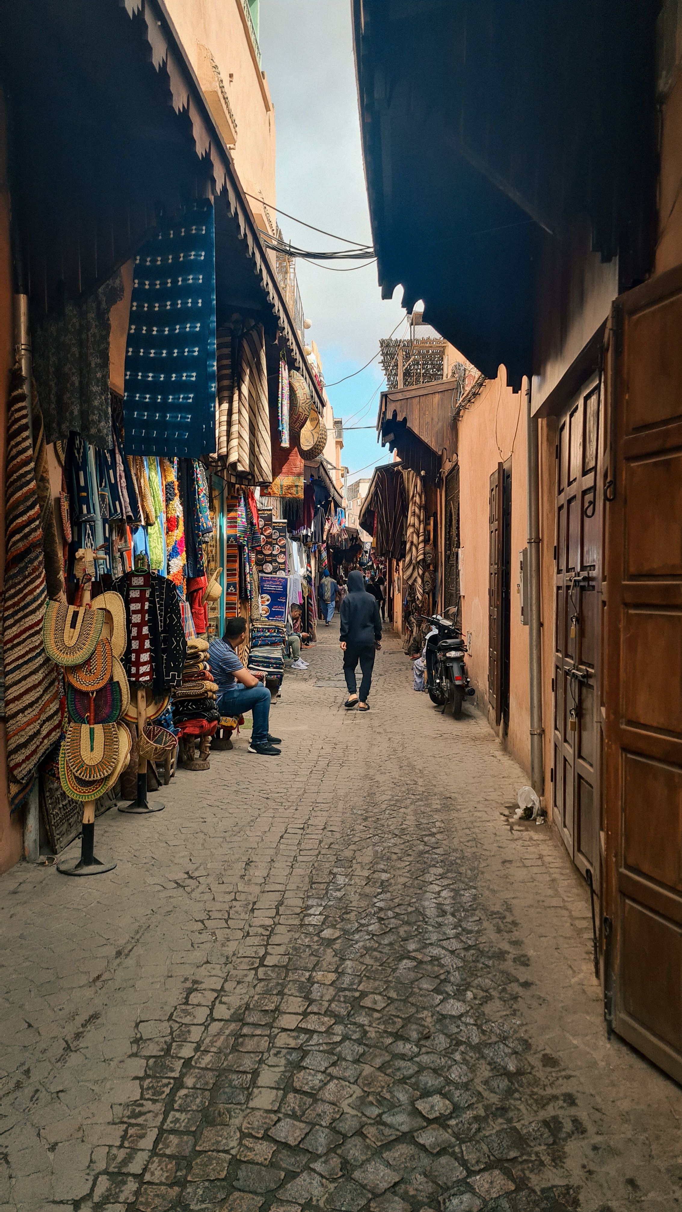 A cobbled souk street lined with woven baskets, rugs and fabrics, Marrakech