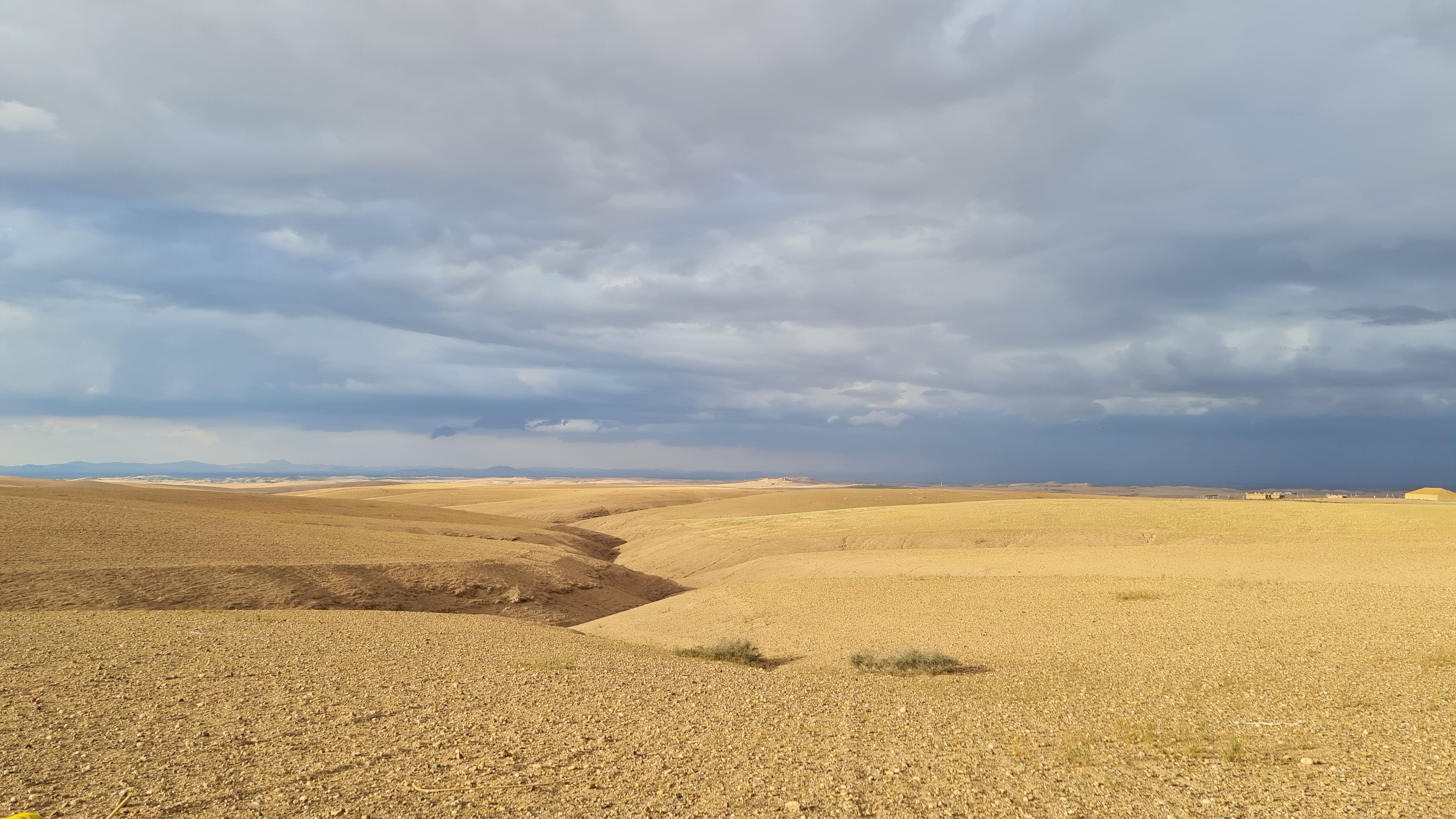 Pale stony desert hills under heavy storm clouds, Agafay Desert