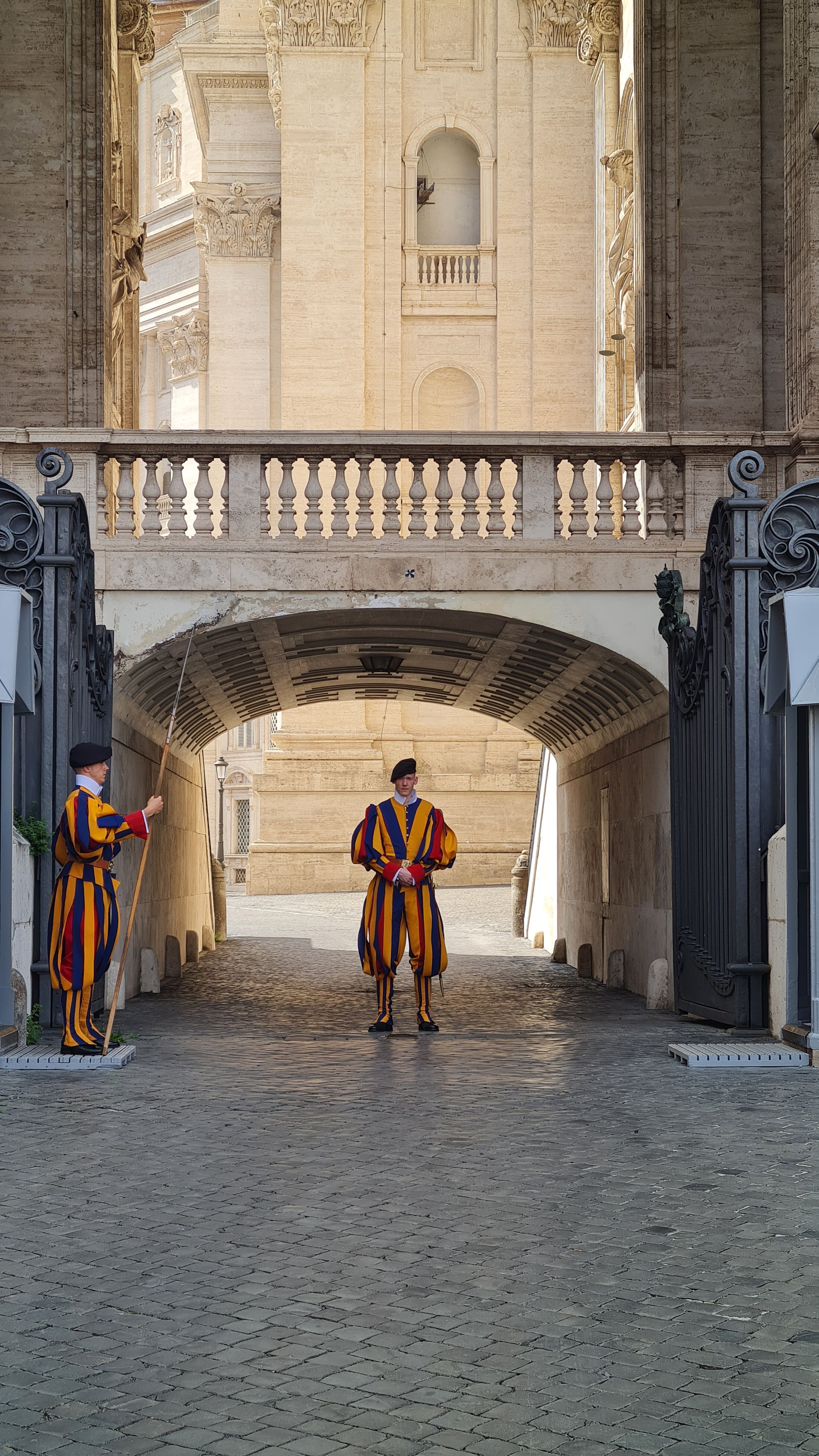 Two Swiss Guards in striped uniforms standing under an archway at the Vatican, Rome